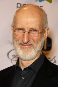 Actor James Cromwell in a black shirt and oval glasses, smiling