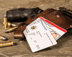 A black .38 snub-nosed revolver encased in a brown leather holster and lying on a countertop. Two concealed carry permits - one for Wisconsin and one for Utah - are stacked atop the holster.