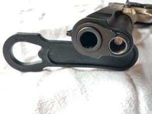 Muzzle and recoil spring of a Remington 1911-style handgun, plus the bushing and a black plastic bushing wrench