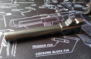 The silver barrel of a Glock 48 9mm semi-automatic pistol lying atop a patterned gun cleaning pad