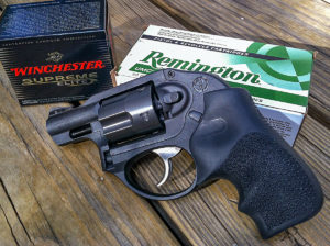 Black Ruger LCR subcompact concealed carry revolver lying next to a box of Winchester ammunition and a box of Remington handgun ammunition.